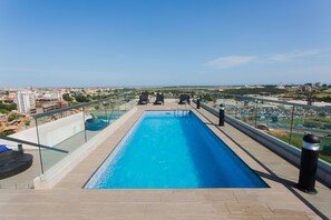 A rooftop swimming pool with a glass balustrade, lounge chairs, and a city view. - Peravi at The Signature (Accra)