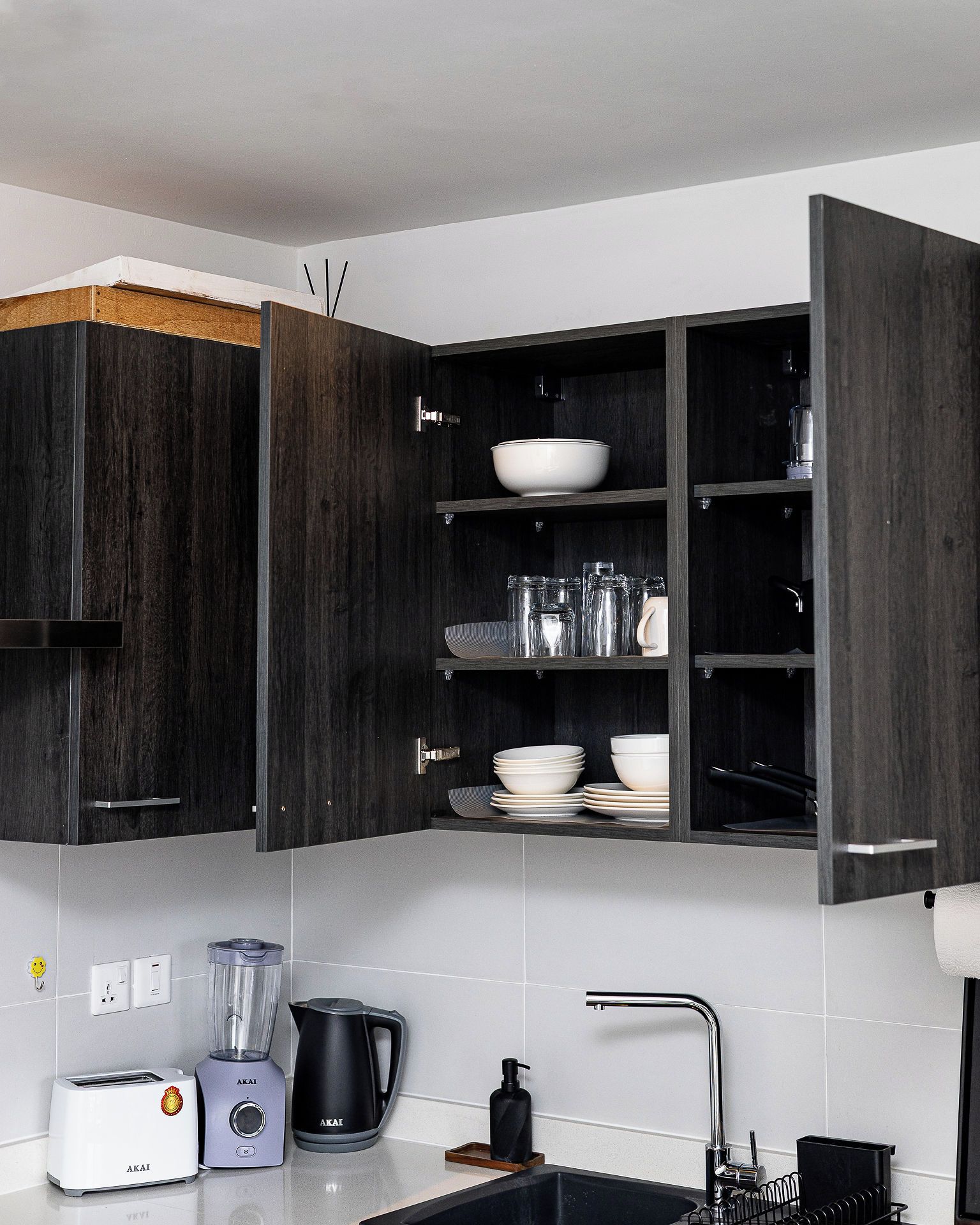 Una cocina moderna con armarios de madera oscura, una estantería empotrada con vajilla, un tostador, una licuadora y un hervidor.