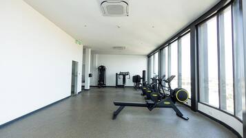 A gym with cardio machines, weightlifting equipment, and large windows.