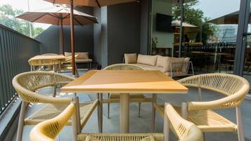 Un área de estar al aire libre con una mesa de madera y sillas de mimbre, un sofá y una sombrilla.