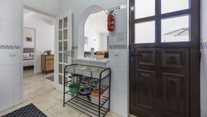 Una cocina con un estante metálico negro que contiene ollas y sartenes, un gabinete de madera y una puerta marrón oscuro.