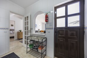 Una cocina con un estante metálico negro que contiene ollas y sartenes, un gabinete de madera y una puerta marrón oscuro.