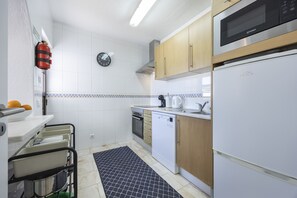 A modern kitchen with white cabinets, a microwave, an oven, and a dishwasher.