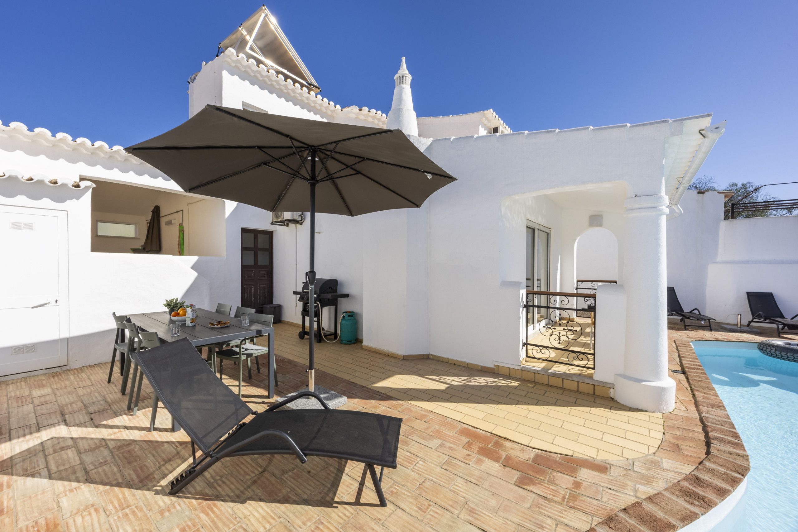 A patio area with a pool, outdoor furniture, and a covered seating area.