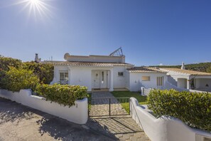 A white villa with a tiled roof, a front door, and a satellite dish.