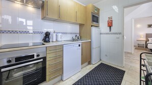 Una cocina moderna con electrodomésticos de acero inoxidable, armarios de madera y salpicadero de azulejos.