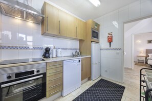 Una cocina moderna con electrodomésticos de acero inoxidable, armarios de madera y salpicadero de azulejos.