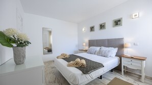 Un dormitorio moderno con cama, mesitas de noche, un espejo y obras de arte en la pared.