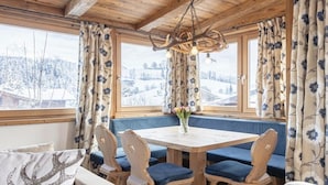 A cozy room with a wooden ceiling, a round table with blue cushioned chairs, and a bench with floral curtains. - Penthouse with 3 bedrooms (Reith bei Kitzbühel)