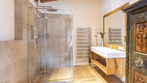 A bathroom with a glass-enclosed shower, a wooden vanity, and a large mirror. - Penthouse with 3 bedrooms (Reith bei Kitzbühel)