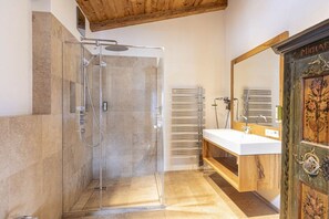 Ein Badezimmer mit einer Duschkabine aus Glas, einem Holzboden und einem großen Spiegel.