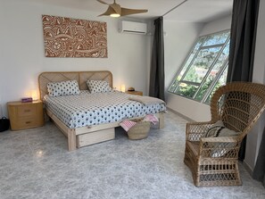 A bedroom with a bed, bedside tables, a chair, a window, and a ceiling fan.