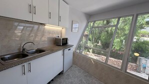 Een moderne keuken met een ingebouwde magnetron, een spoelbak van roestvrij staal en witte keukenkastjes.