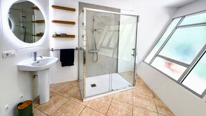 Een moderne badkamer met een douchecabine van glas, een wastafel en een spiegel.