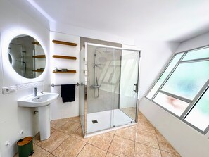 Une salle de bain moderne avec une douche à parois de verre, un lavabo et un miroir.