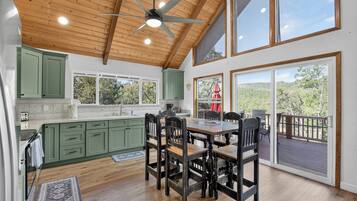 A spacious kitchen with a dining area, large windows, and a ceiling fan.