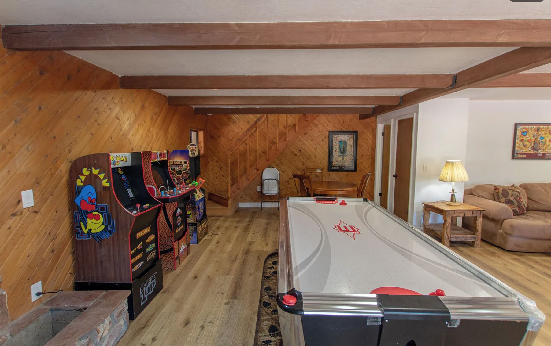 A room with a pool table, arcade machines, a dining table, and a couch.
