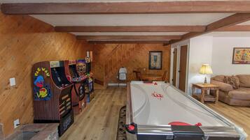 A room with a pool table, arcade machines, a dining table, and a couch.