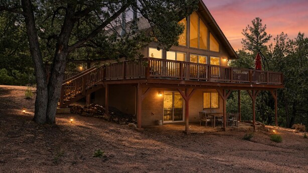 A two-story log cabin with a balcony, surrounded by trees. - Pine Cabin w View, Fireplace, Deck & Game Room (Pine)