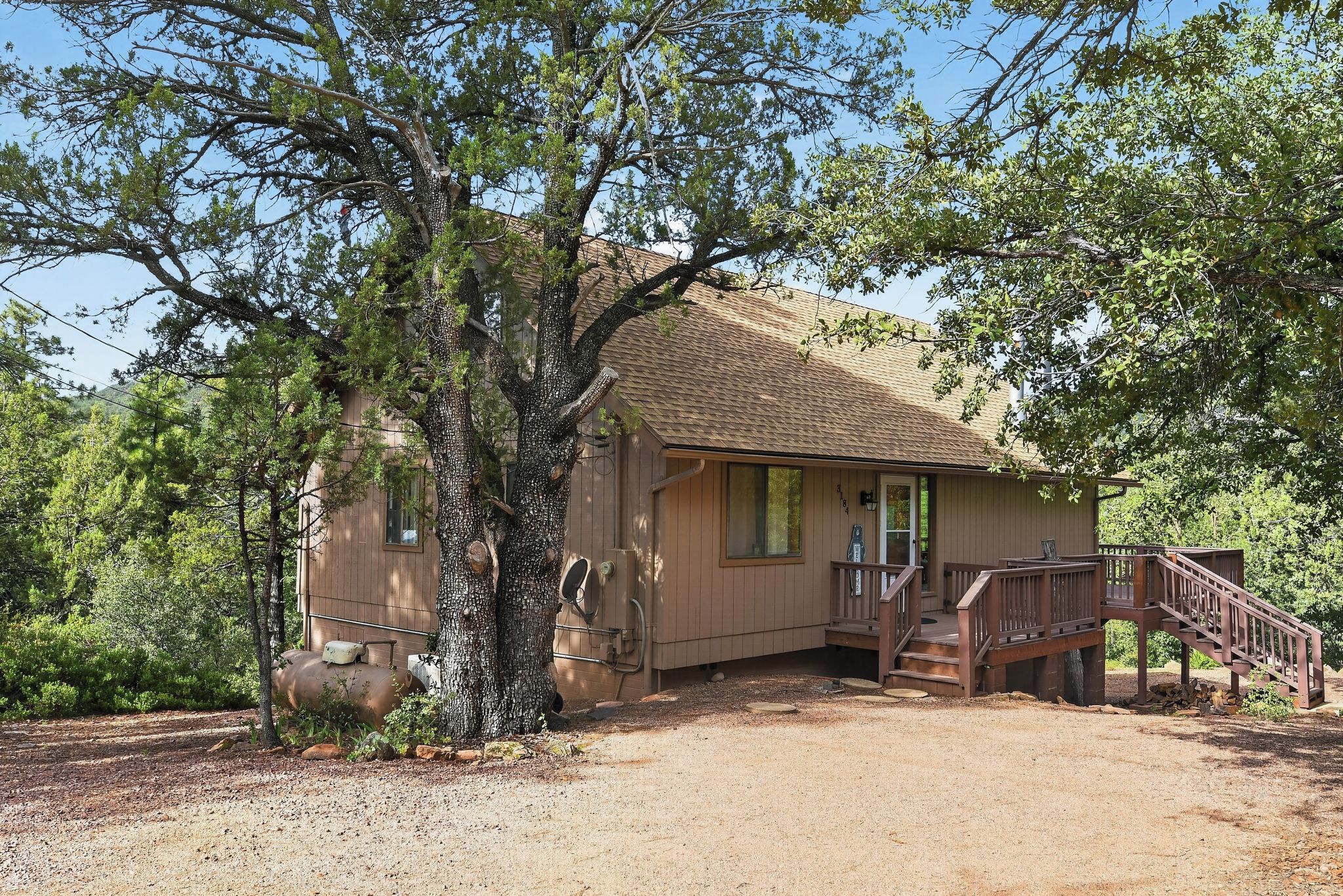 A single-story house with a wooden deck and a staircase leading to the entrance.