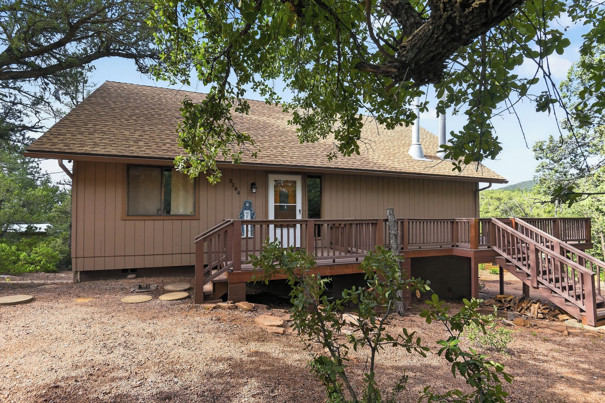 A two-story house with a wooden deck and a staircase leading to the front door.