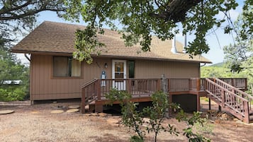 A two-story house with a wooden deck and a staircase leading to the front door.