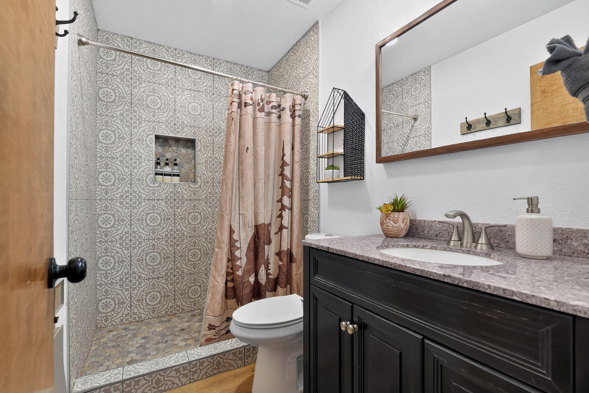 A bathroom with a shower, toilet, sink, and a mirror.