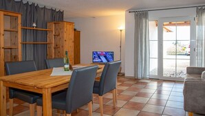 A dining area with a wooden table and chairs, a television, and a view through a glass door. - Holiday apartment with 1 bedroom (Meersburg)