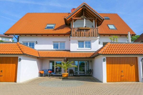 Ein zweistöckiges Haus mit rotem Ziegeldach, einem Balkon und einer Garage.
