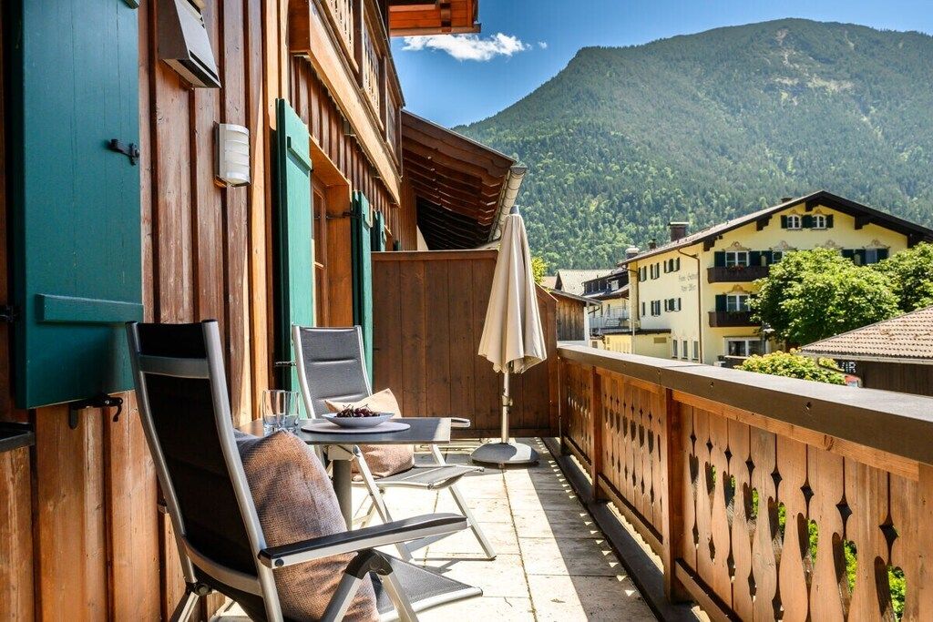 A balcony with outdoor seating, a mountain view, and traditional wooden architecture.