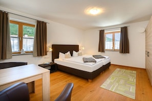 Een slaapkamer met een bed, nachtkastjes, een bureau en een stoel.