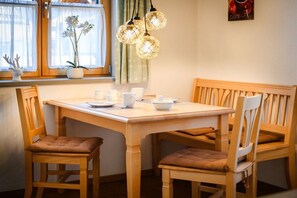 Een eethoek met een houten tafel en stoelen, een potorkidee en een wandlamp.