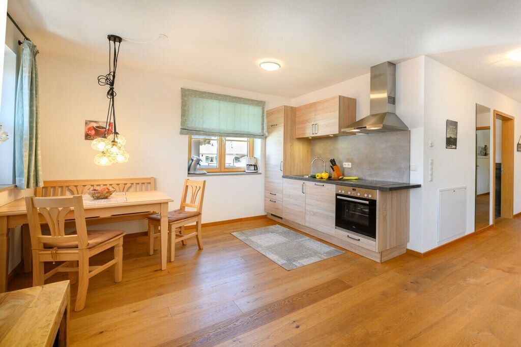 A modern kitchen with wooden cabinets, a built-in oven, and a dining area with a wooden table and chairs.