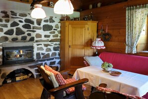 Een gezellige kamer met een stenen muur, een open haard, houten meubels en een tafel met een witte tafelkleed.