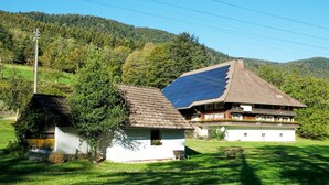 Tipico chalet con tetto spiovente e pannelli solari, immerso nel verde e circondato da dolci colline.