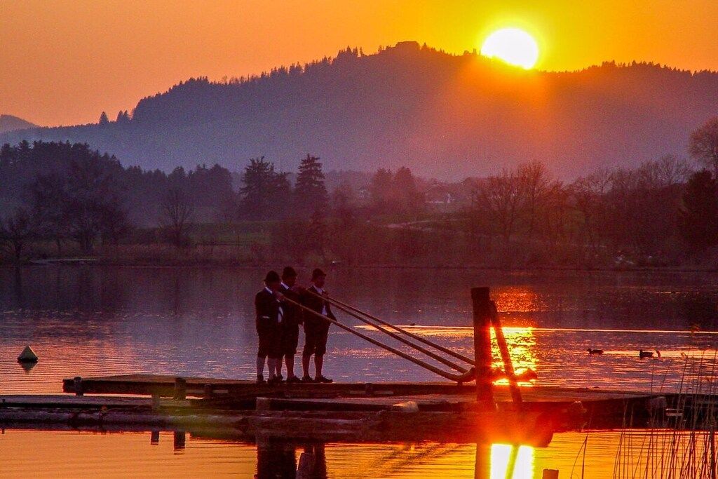 A sunset over a body of water with a dock and people standing on it.