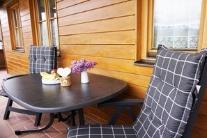 Ein runder Tisch mit kariertem Kissen, eine Vase mit violetten Blumen und ein Teller mit Essen.