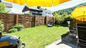 A backyard with a grill, patio furniture, and a yellow umbrella. - Four Seasons || Bad Urach (Bad Urach)
