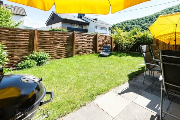 A backyard with a grill, patio furniture, and a yellow umbrella. - Four Seasons || Bad Urach (Bad Urach)