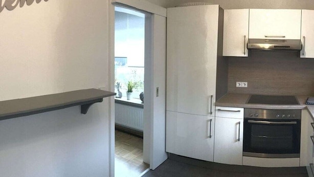 A compact kitchen with white cabinets, a stainless steel oven, and a window providing natural light. - Four Seasons || Bad Urach (Bad Urach)
