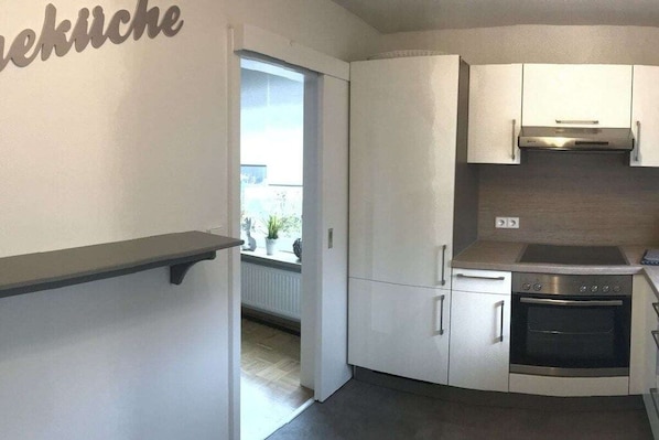 A compact kitchen with white cabinets, a stainless steel oven, and a window providing natural light. - Four Seasons || Bad Urach (Bad Urach)