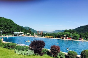 A swimming pool with people, surrounded by greenery and hills. - Four Seasons || Bad Urach (Bad Urach)