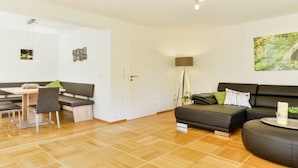 A modern living room with a sofa, a dining table with chairs, and a lamp. - Four Seasons || Bad Urach (Bad Urach)