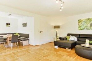 A modern living room with a sofa, a dining table with chairs, and a lamp. - Four Seasons || Bad Urach (Bad Urach)