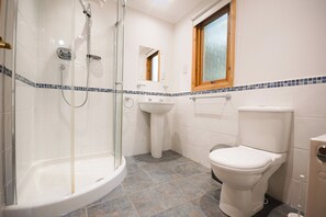 Ein Badezimmer mit einer Duschkabine, einem Standwaschbecken und einer Toilette.