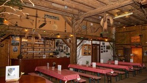 A restaurant interior with wooden beams, red and white checkered tables, and a bar area with shelves of bottles. - Holiday apartment with 1 bedroom (Meersburg)