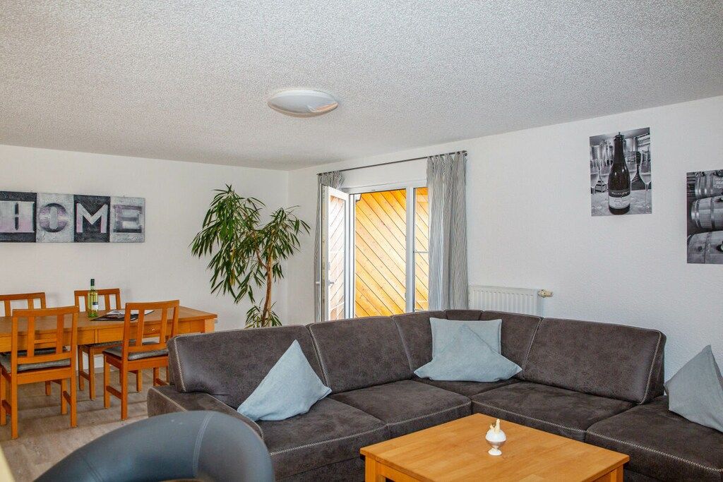 Een woonkamer met een bank, een salontafel, een eettafel met stoelen en een potplant.