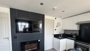 Uma cozinha moderna com TV integrada, lareira e forno de aço inoxidável.