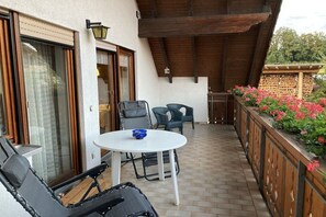 Een terras met een tafel en stoelen, een hangmat en een houten omheining met bloemen.