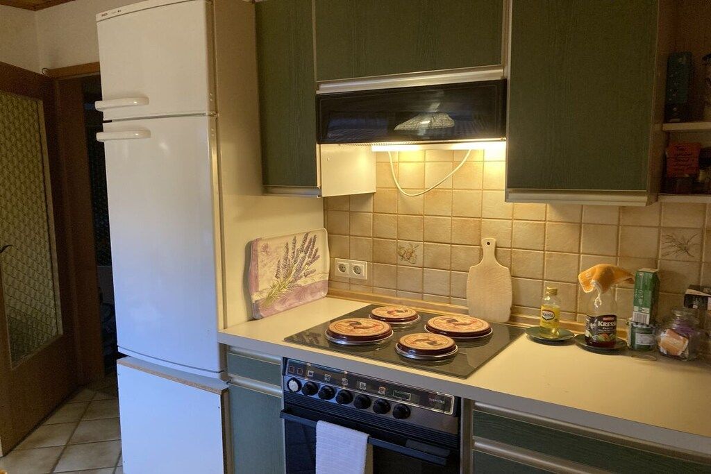 Cocina con refrigerador, estufa y horno. Hay gabinetes, una encimera y varios utensilios de cocina.